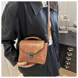 Détail d'un sac à bandoulière marron vintage avec serrure en métal et poignée