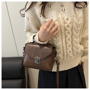 Détail de la texture cuir marron vintage et du grand fermoir métallique sur le sac à main
