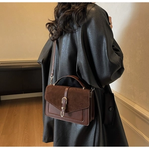Detail of vintage brown shoulder bag with metal buckle and multi-compartment texture
