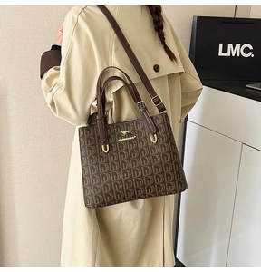 Sac cabas marron à monogramme avec logo kangourou doré porté par un mannequin