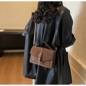 Detail of vintage brown crossbody bag featuring suede patchwork and gold buckle closure