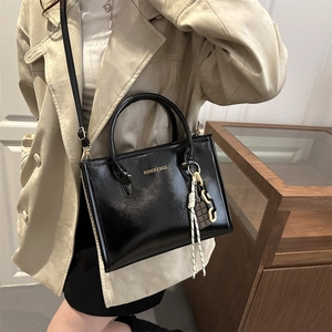 Sac fourre-tout en cuir brillant noir avec lettrage doré porté en bandoulière