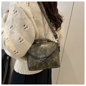 Vue détaillée du sac bandoulière rétro en cuir vert avec fermoir tournant sur modèle