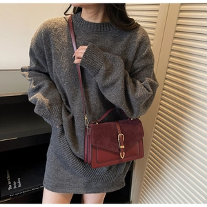 Detail of burgundy vintage crossbody bag showing faux leather textures and golden buckle
