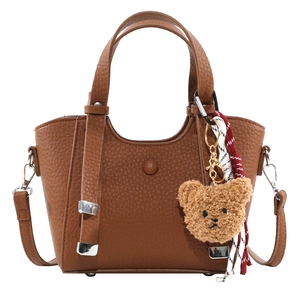 Brown lychee texture leather tote bag with plush bear charm and woven tassel strap