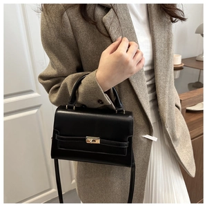 Detail of the black leather bag with gold-tone twist lock and adjustable shoulder strap