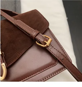 Detail of brown leather and suede shoulder bag showing stitching and gold metal buckle