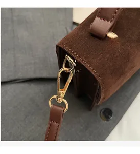 Close-up of premium brown suede crossbody bag with textured leather and gold hardware