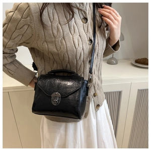 Détail d'un sac bandoulière vintage en cuir PU huilé noir avec une boucle métallique