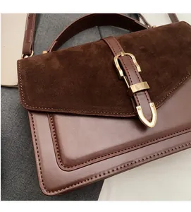Close-up of brown suede and smooth leather crossbody bag with golden metal buckle