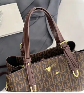 Détail d'un sac cabas marron avec logo kangourou doré et des poignées en cuir