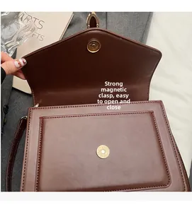 Detail view of the strong magnetic snap closure on a wine red leather crossbody bag