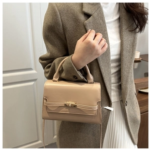 Detail of elegant beige crossbody bag with top handle and metallic buckle closure