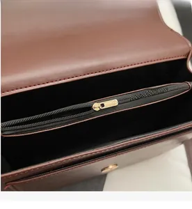 Detail showing smooth gold metal zipper and multi-compartment interior of brown handbag
