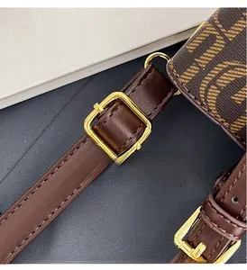 Détail de la boucle dorée sur la bandoulière en cuir marron du sac à main monogramme