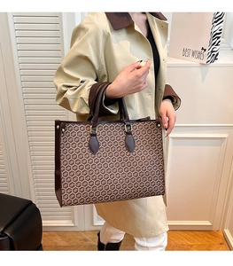 Detail of a large tote bag with geometric print and brown leather handles for daily commute