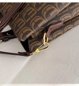 Gros plan du fermoir mousqueton doré et du cuir imprimé d'un sac cabas marron élégant
