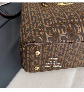 Détail des rivets en métal doré sur le fond d'un sac cabas marron à monogramme