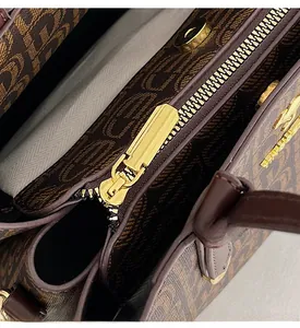 Détail de la fermeture éclair dorée et de la texture du cuir à monogramme brun