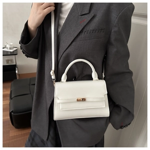 White leather handbag styled with a grey oversized blazer in a minimalist indoor setting