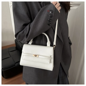 Detailed view of a white leather crossbody bag with a gold twist lock and a top handle