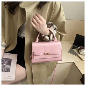 Close-up of pink leather small square bag with gold metal twist lock and top handle