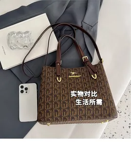 Détail d'un sac cabas monogramme marron rétro avec poignées en cuir et garnitures dorées