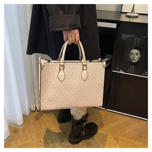 Close-up of vintage monogram tote bag with beige geometric pattern and leather handles