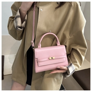 Detail of pink leather handbag with gold metal lock worn with a beige trench coat