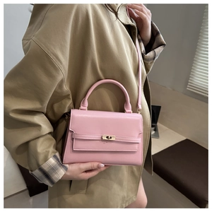 Detail of pink leather trapezoid handbag with gold rotating lock on a trench coat model