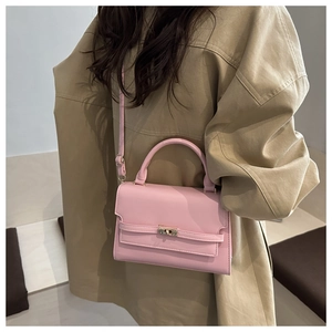 Detail of pink leather crossbody bag with golden metal turn-lock and top handle on coat