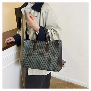 Detail view of the vintage monogram pattern and brown leather straps on the tote bag