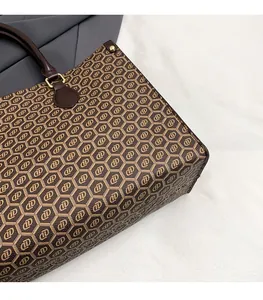 Close-up of vintage monogram tote bag with brown leather handles and gold metal rivets