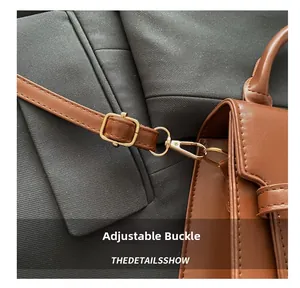 Detailed shot of brown leather bag featuring golden metal buckles and adjustable strap