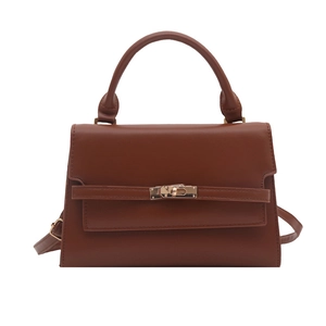 Brown leather crossbody handbag with top handle and metal buckle on white background