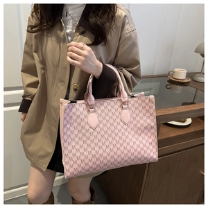 Pink tote bag with M-letter print held by a model in a stylish trench coat