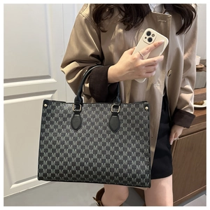 Détail du sac cabas imprimé M vintage avec anses en cuir noir et ferrures en métal doré