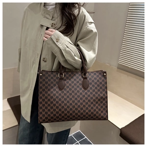 Detail view of a vintage monogram tote bag with brown leather handles and gold metal accents