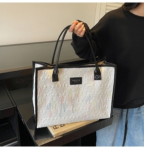 Détail du sac cabas blanc avec broderie ondulée colorée et anses en cuir noir robuste