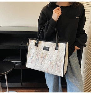 Détail du grand sac cabas blanc avec broderie arc-en-ciel et écusson en cuir de mode