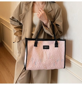 Detail of pink quilted tote bag with colorful embroidery and black leather handles