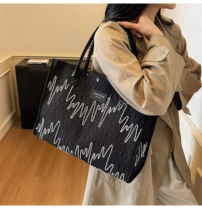 Détail du sac cabas matelassé noir avec broderie blanche et écusson en cuir NEW YORK