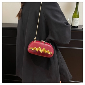 Detail of red semicircular evening bag with golden wave metal trim and fine chain strap