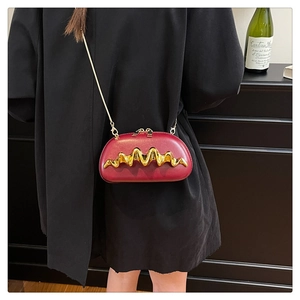 Detail of dark red evening bag featuring gold wave metal trim and fine chain strap