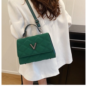 Détail du sac à main matelassé vert foncé avec boucle en V en métal et cuir texturé