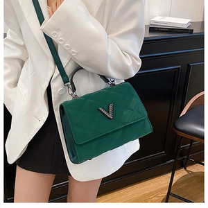 Détail du sac à main vert foncé matelassé avec fermoir en V métallique et bandoulière