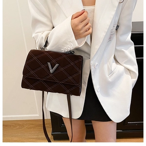 Détail du sac bandoulière matelassé marron foncé avec logo en V argenté et texture mate