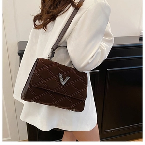 Gros plan du sac en daim marron foncé matelassé avec un logo en métal argenté en V