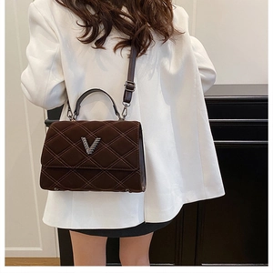 Gros plan d'un sac à main matelassé marron foncé avec boucle en V sur un mannequin