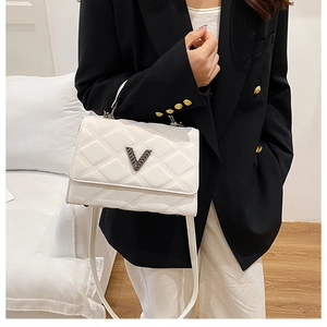 Détail du sac à main matelassé blanc avec fermoir métallique en V et texture en cuir synthétique
